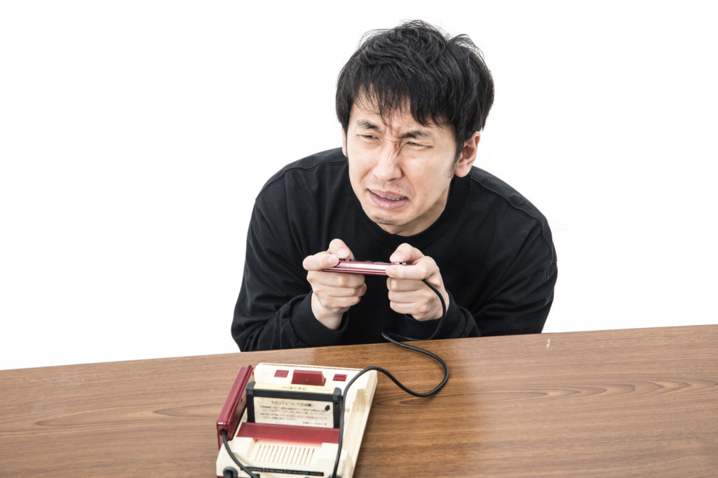 ファミコンを握って難しい顔をする男性